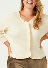Load image into Gallery viewer, Woman wearing a cream-colored blouse with ruffled details on a white background