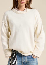 Load image into Gallery viewer, Person wearing a cream sweater and blue jeans against a beige background