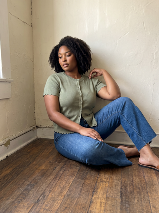 Plus size woman wearing jeans, a graphic tee, long cardigan and boho hat.