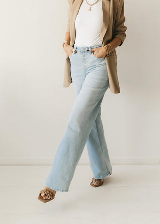 Woman kicking leg out in wide stride wearing light washed wide leg jeans and heels.