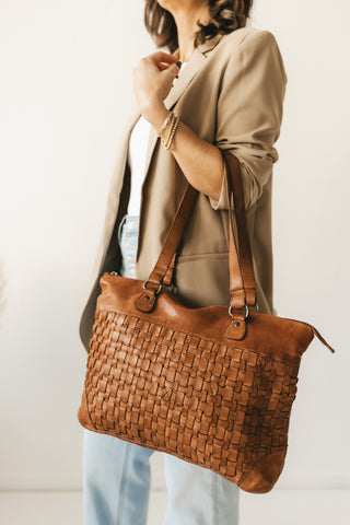 Woman's arm holding leather tote bag wearing bracelets