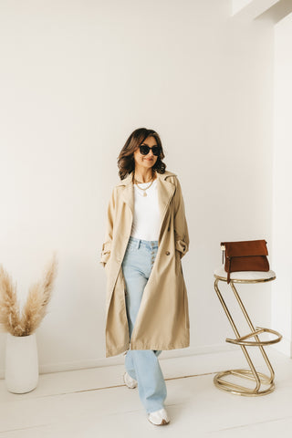 Woman walking with hand in trench coat pocket, coat swinging open.