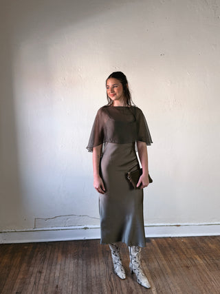 SUNDAY EDITION BY LE LIS boat neck cape slip midi dress with flowing fabric and elegant silhouette, shown on a mannequin.