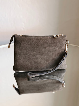 Olive suede wristlet bag by MOST WANTED USA with a sleek design and wrist strap, perfect for carrying essentials.