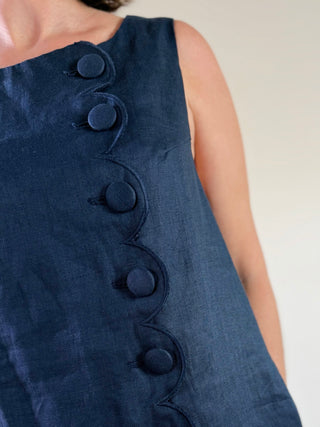 MABLE Margot scalloped linen mini dress in light fabric with scalloped hem, displayed on a hanger against a neutral background.