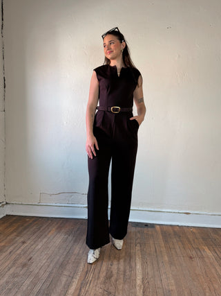 Dark brown sleeveless ponte wide leg jumpsuit by Sunday Edition by Le Lis, shown on a model in a stylish indoor setting.
