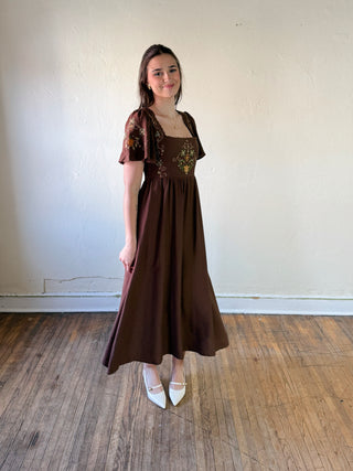 Blue Pepper Meadow Song embroidered midi dress with floral pattern and flowing fabric, showcased on a hanger.