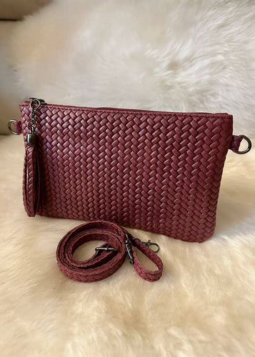 Woven red handbag with a strap on a white fur background
