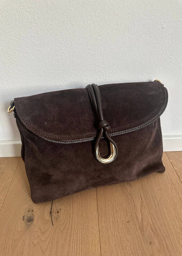Brown suede handbag with a gold clasp on a wooden floor.