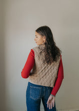 Load image into Gallery viewer, Person wearing a beige quilted vest over a red long-sleeve shirt with blue jeans against a plain background
