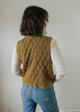 Load image into Gallery viewer, Person wearing a quilted mustard yellow vest over a white shirt and blue jeans against a plain background
