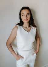 Load image into Gallery viewer, Woman wearing a white sleeveless top and pants against a plain wall.
