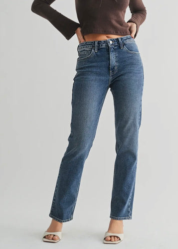 Person wearing blue jeans and a brown top on a white background