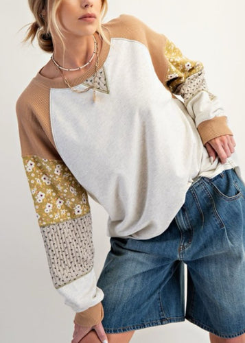 Woman wearing a patchwork sleeve pullover and denim shorts on a white background