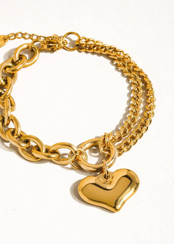 Gold chain bracelet with a heart-shaped charm on a white background