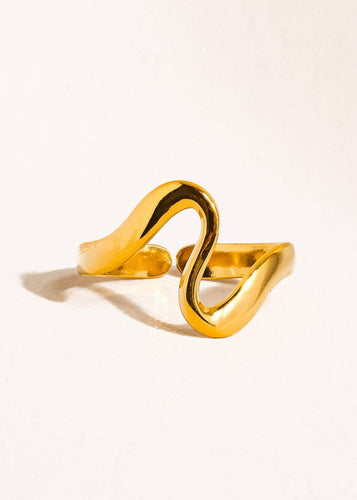 Gold ring with a wavy design on a light beige background