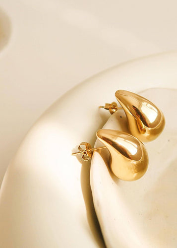 Gold earrings on a beige background