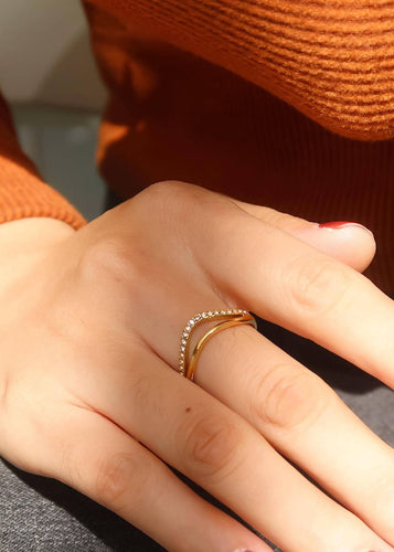 Close-up of a hand wearing two gold rings on a blurred background