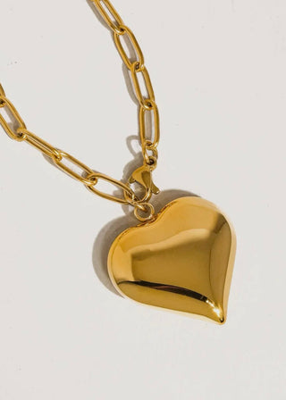 Gold heart-shaped pendant on a gold chain against a white background