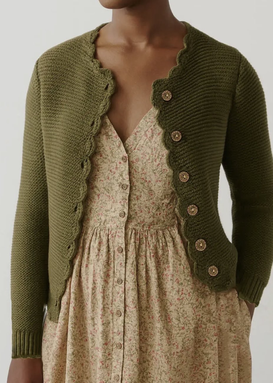 Green knitted cardigan over a floral dress on a neutral background