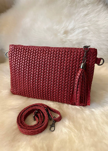 Red woven handbag with matching strap on a white fur background