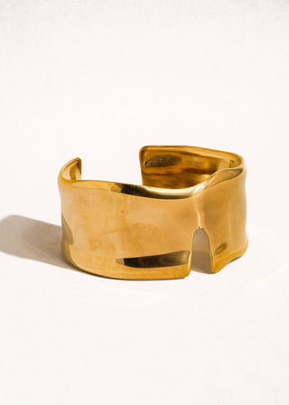 Gold cuff bracelet on a white background