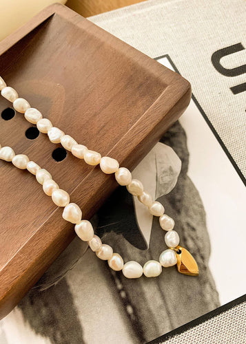 Pearl necklace with a gold tag on a wooden tray
