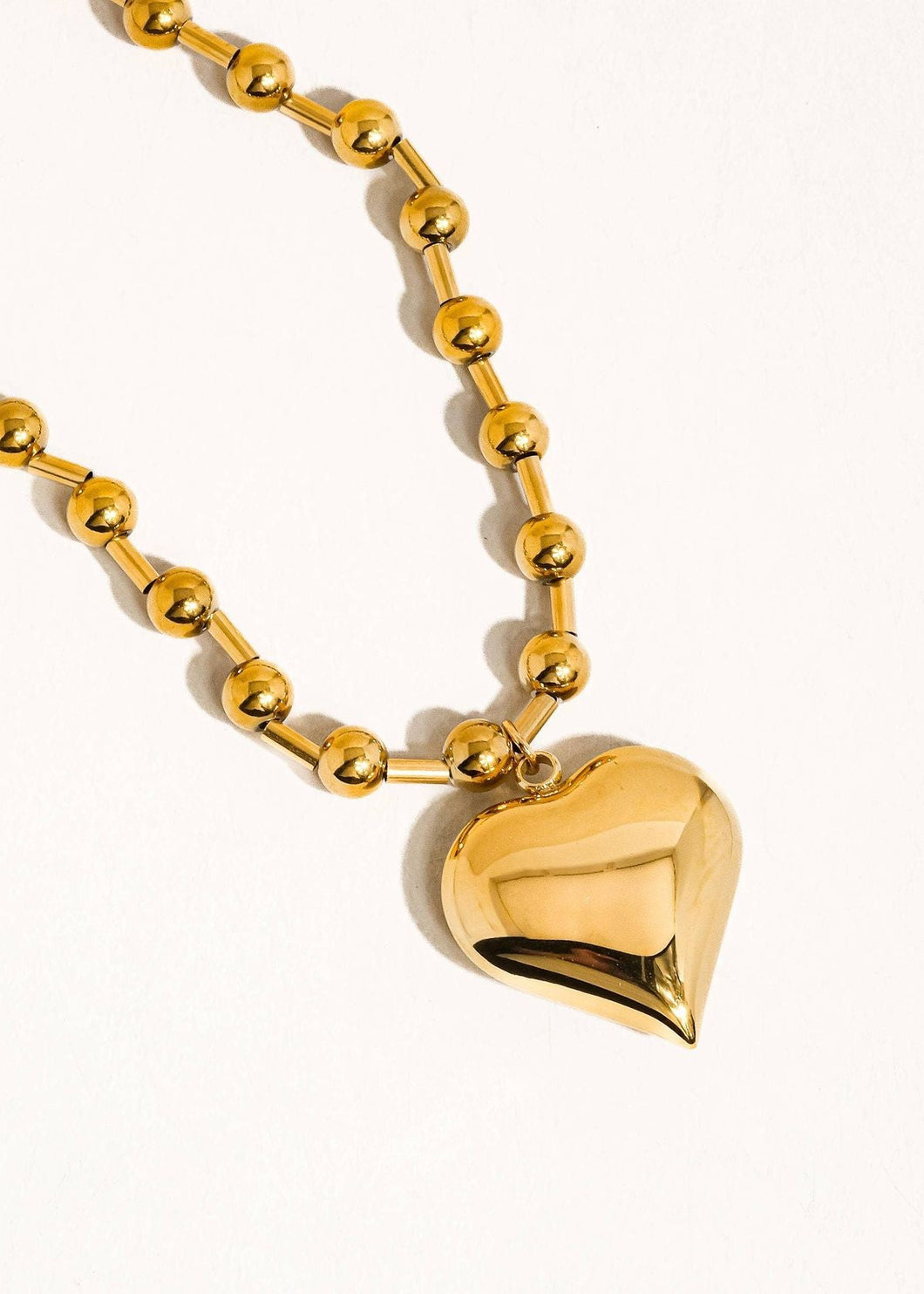 Gold heart-shaped pendant on a gold chain against a white background
