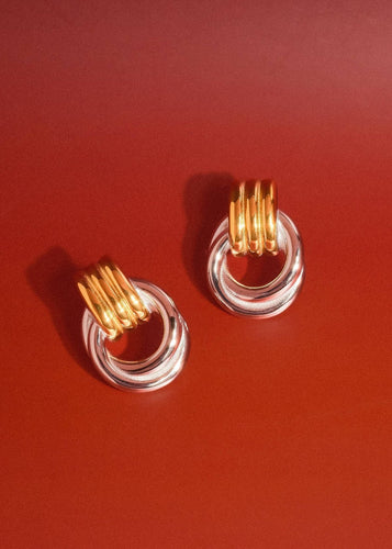 Gold and clear hoop earrings on a red background