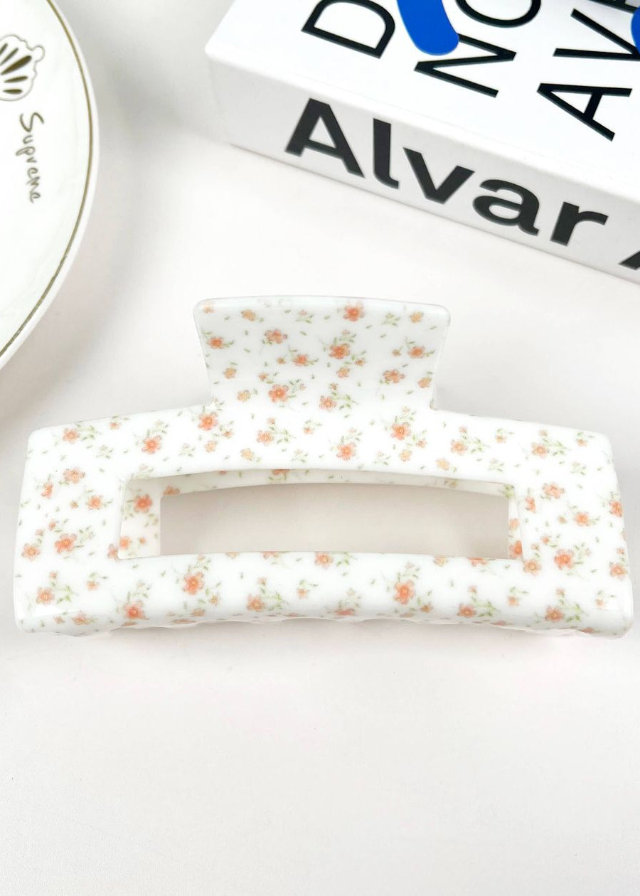 Floral patterned hair clips on a white surface with a brand name visible.