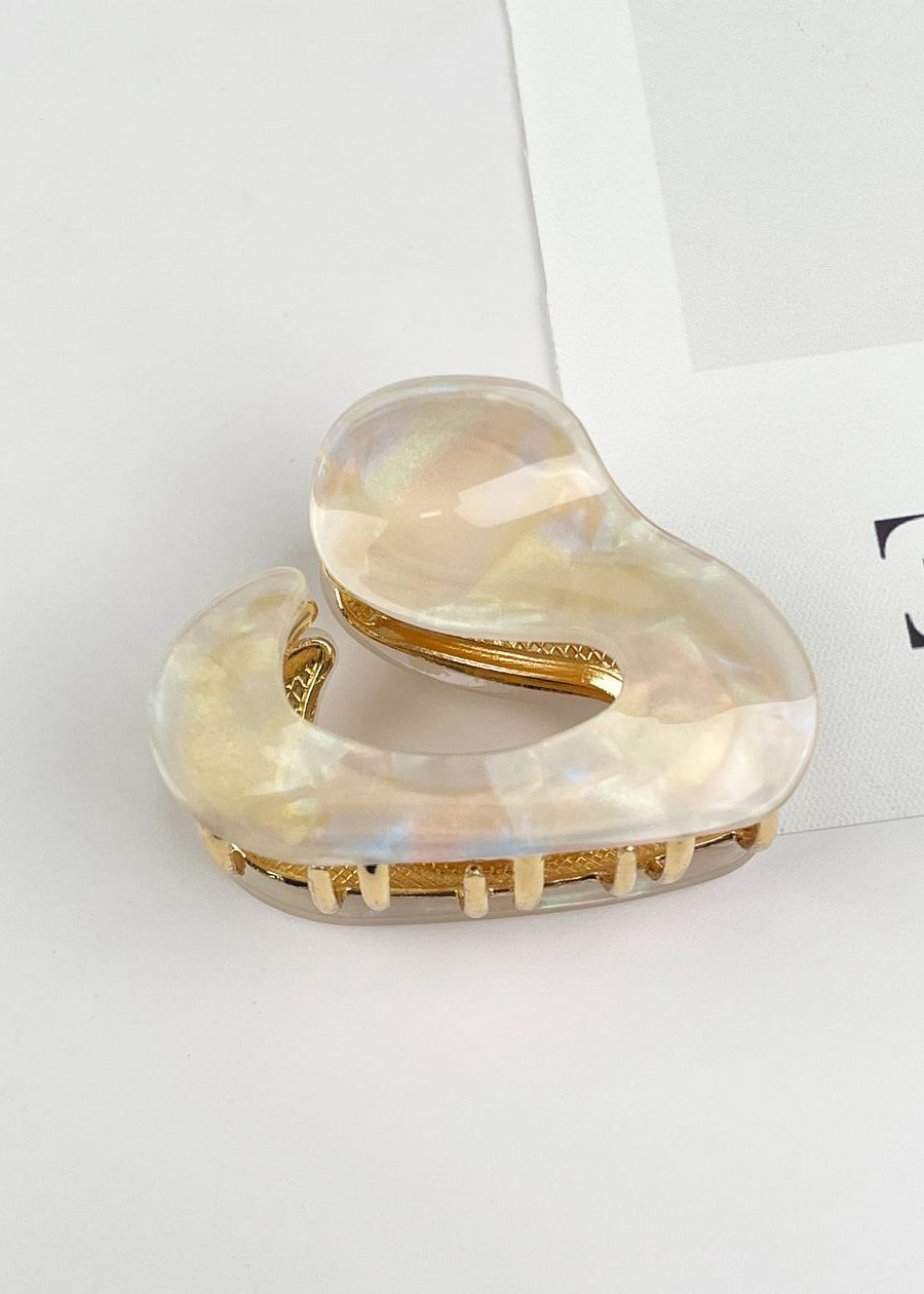 Heart-shaped hair clip with gold accents on a light gray background