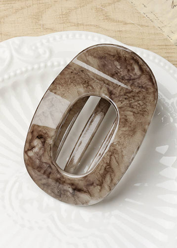 Marble-patterned soap dish on a white textured surface with a wooden background