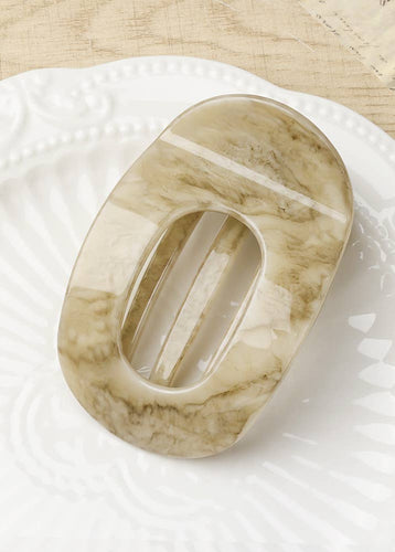 Marble-patterned soap dish on a white plate with a wooden surface background