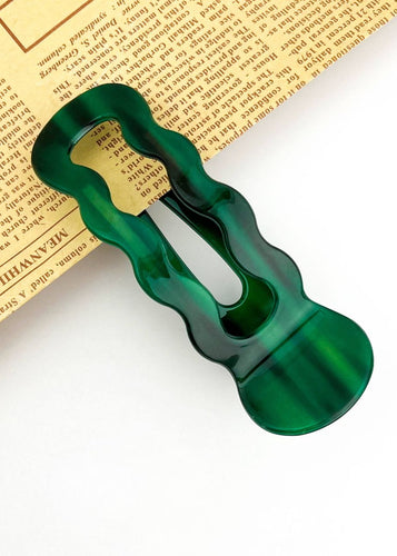 Green hair clip on a piece of paper with text