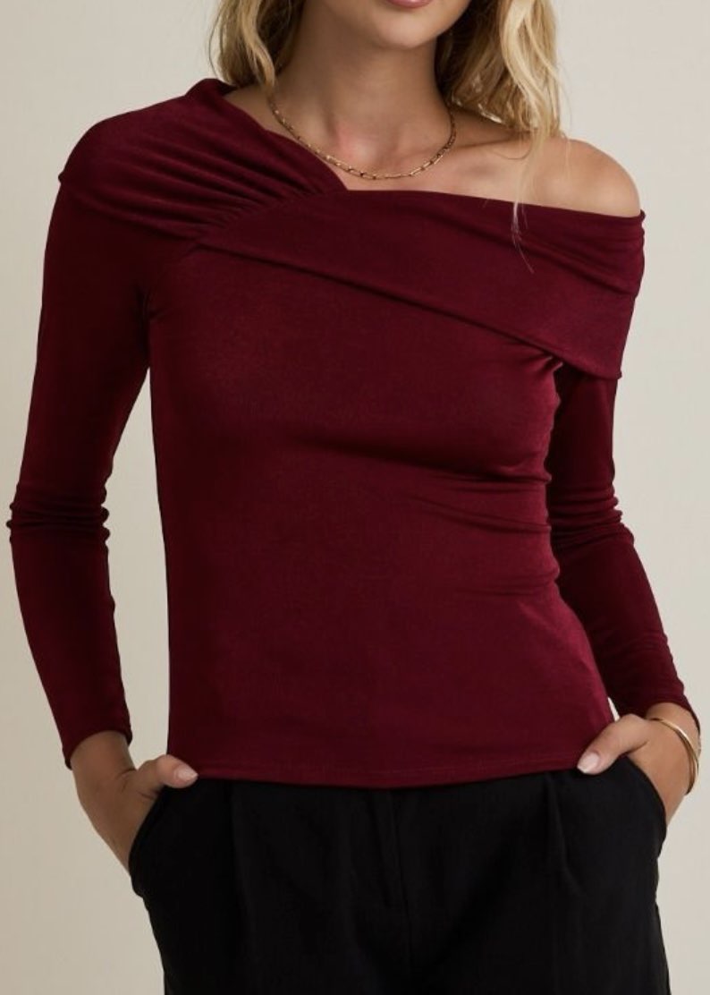 Maroon off-shoulder top worn by a person on a beige background