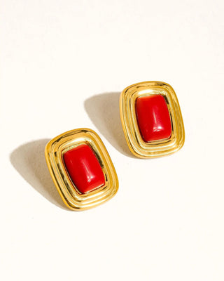 Pair of gold earrings with red stones on a white background