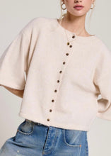 Load image into Gallery viewer, Person wearing a cream cardigan with brown buttons and blue jeans on a plain background
