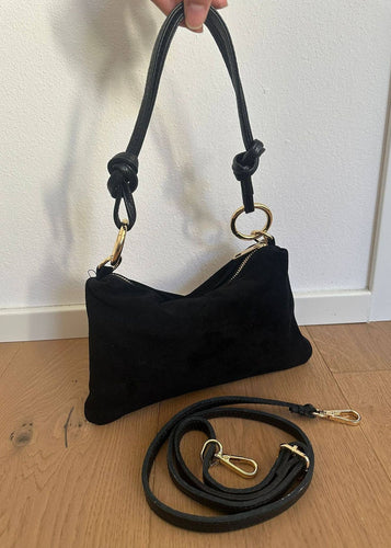 Black handbag with gold accents on a wooden floor