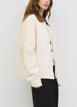 Load image into Gallery viewer, Woman wearing a cream jacket and black pants against a white background
