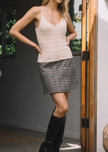 Load image into Gallery viewer, Woman wearing a beige knit top and plaid skirt with black knee-high boots indoors.
