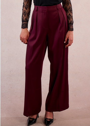 Maroon wide-leg pants worn by a person on a beige background