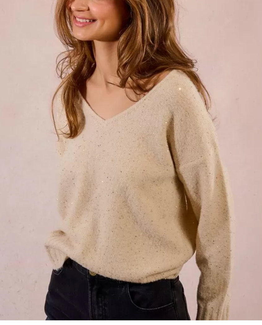 Woman wearing a beige sweater against a plain background