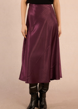 Load image into Gallery viewer, Person wearing a purple satin skirt and black boots on a beige background

