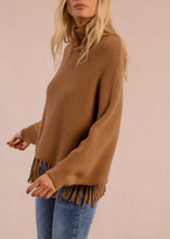 Load image into Gallery viewer, Woman wearing a brown fringed sweater and blue jeans on a beige background

