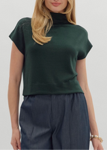 Load image into Gallery viewer, Woman wearing a green turtleneck top and dark pants on a plain background
