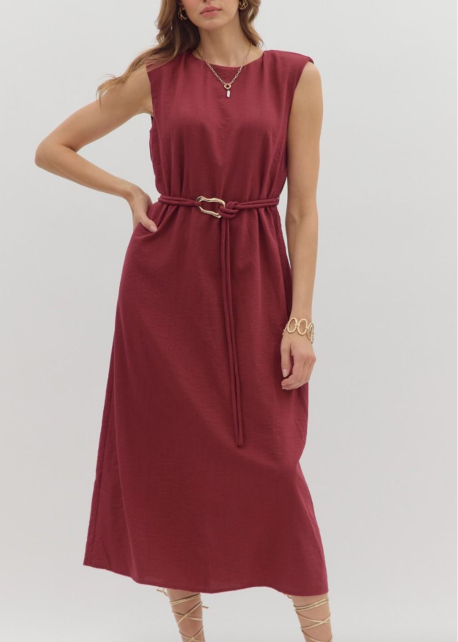 Woman wearing a burgundy dress with a belt on a white background