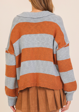 Load image into Gallery viewer, Person wearing a striped sweater with orange and gray horizontal stripes on a beige background
