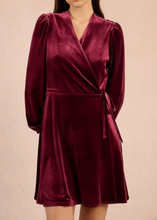 Load image into Gallery viewer, Maroon velvet dress with long sleeves on a beige background

