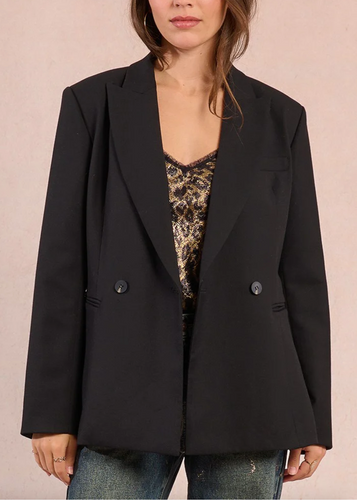 Person wearing a black blazer over a leopard print top on a beige background