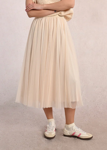 Person wearing a beige pleated skirt and white sneakers on a plain background
